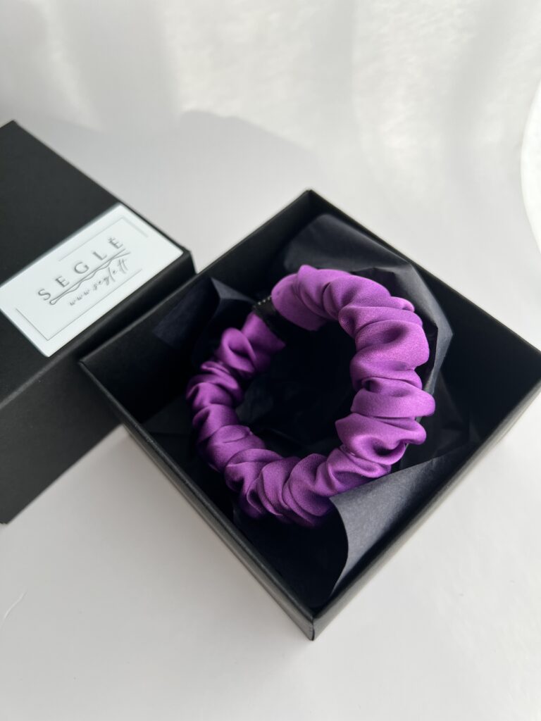 Tamsiai violetinės spalvos šilkinė plaukų gumytė juodoje dėžutėje