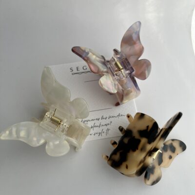 Trys drugelio formos plaukų segtukai baltame fone