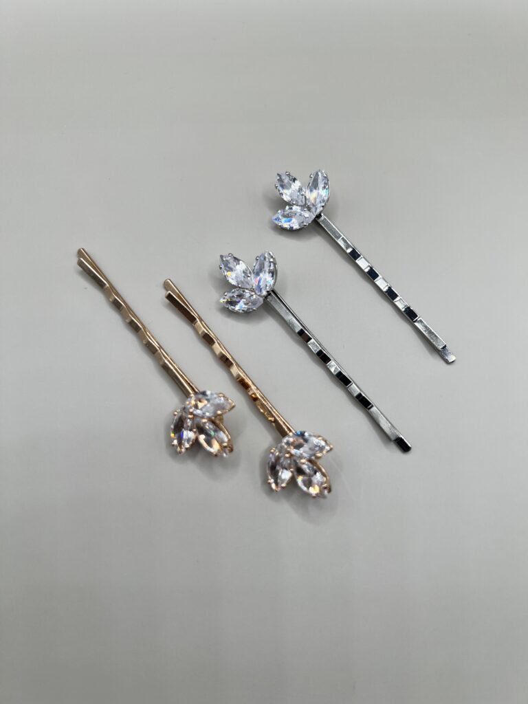 Metaliniai plaukų segtukai dekoruoti blizgančiais cirkoniais, kurie išdėstyti žiedlapio forma. Segtukai sidabro ir aukso spalvos