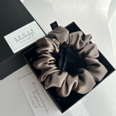 Natūralaus šilko rusvai pilkos spalvos plaukų gumytė juodoje dėžutėje baltame fone