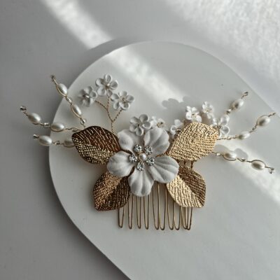 Metalinė aukso spalvos sagė vestuvinėms plaukų šukuosenoms. Sagė dekoruota baltomis plastikinėmis gėlėmis